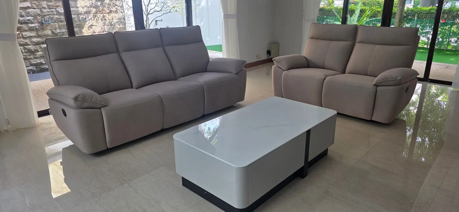 The furnished living room at Villa Mont Kiara — a sectional recliner set around a coffee table, facing the pool.